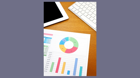 laptop keyboard and printed data charts