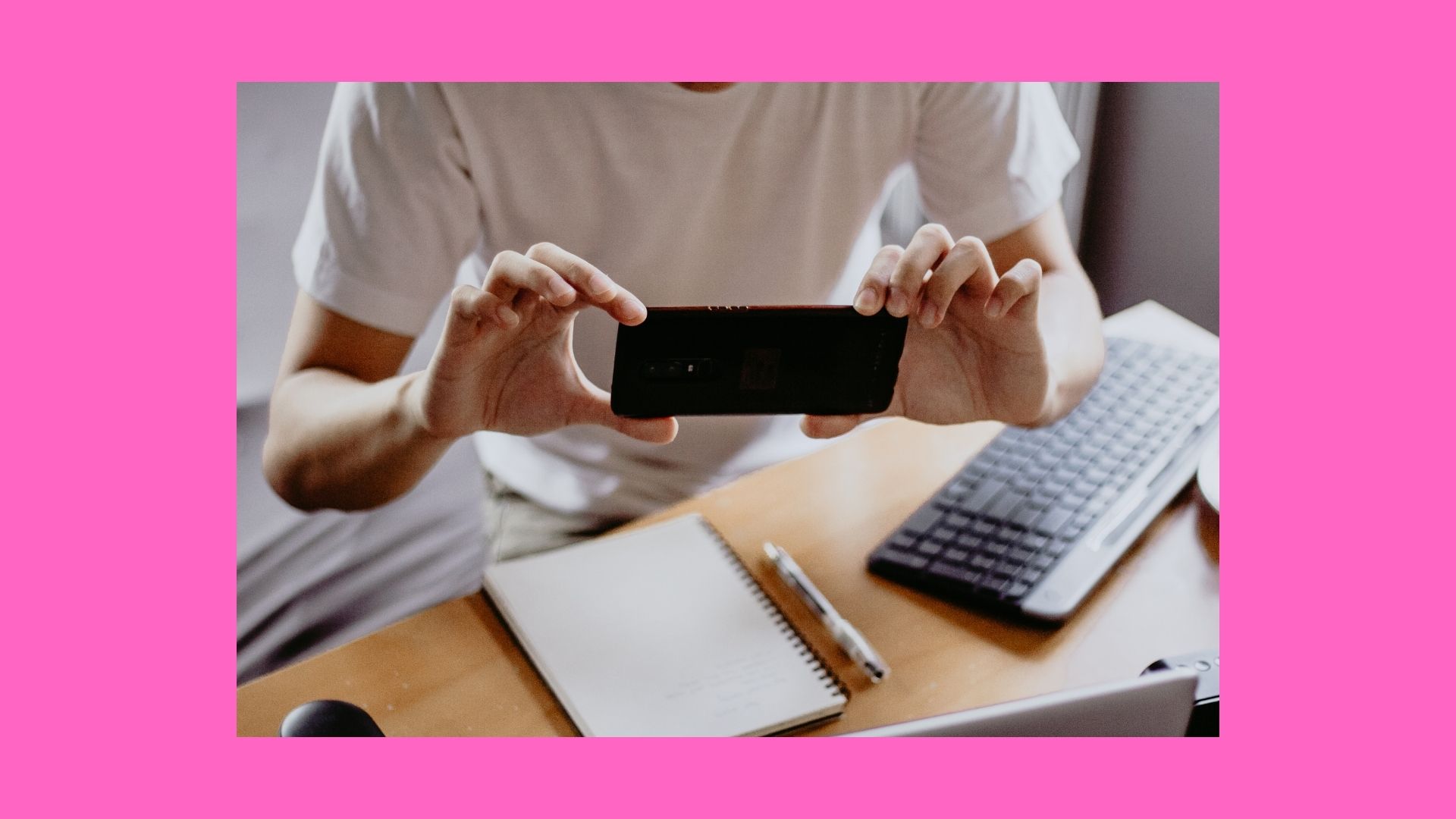 photo of a person holding a phone with a keyboard and notebook